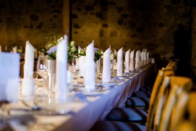 Tischgedeck mit weißen Servietten und Blumendekoration in einem festlichen Raum.