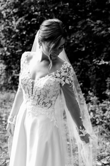 Hochzeitsbraut in einem eleganten Kleid mit Spitze und Schleier, Blick nach unten.