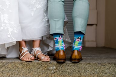 Braut und Bräutigam stehen nebeneinander, stilvolle Schuhe und bunte Socken sichtbar.