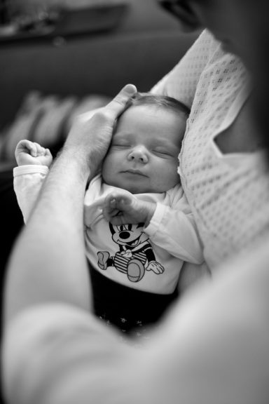 Ein schlafendes Baby wird sanft in den Armen gehalten.