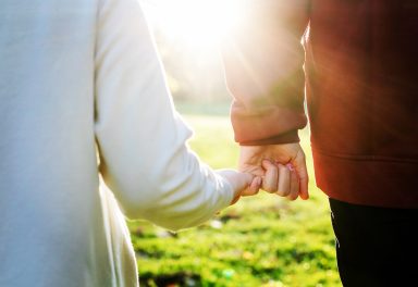 Händchen haltendes Paar in der Natur bei Sonnenlicht.